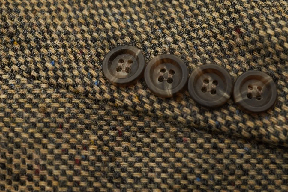 Botones cosidos en una chaqueta de tweed