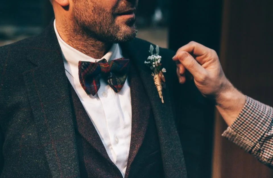 Hombre ajustándose la chaqueta de un traje con pajarita