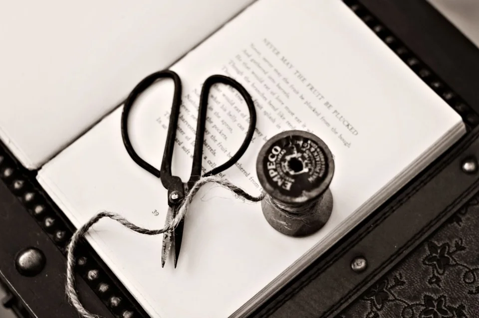 Tijeras de costura y carrete de hilo sobre un libro